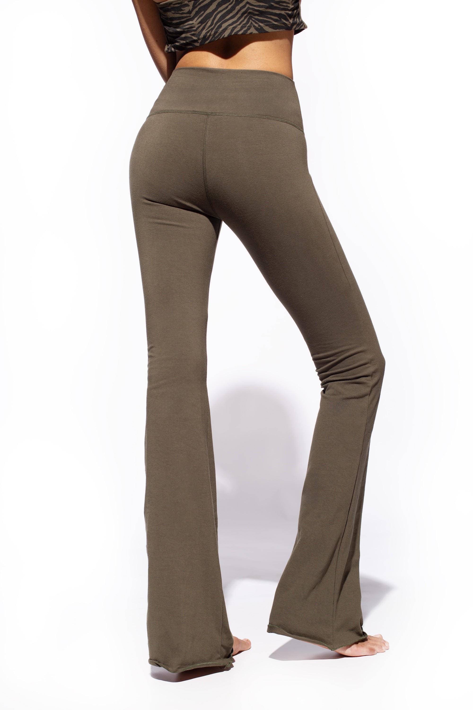 Model wearing olive green color Flares made out of cotton lycra from Funky Simplicity. Shown from the back with a white background
