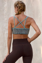Woman wearing a light blue with Brown Argus print sports bra and brown leggings against a neutral background