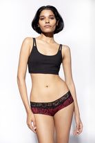 Model wearing red black feather underwear with a black cross back bra shown from the front