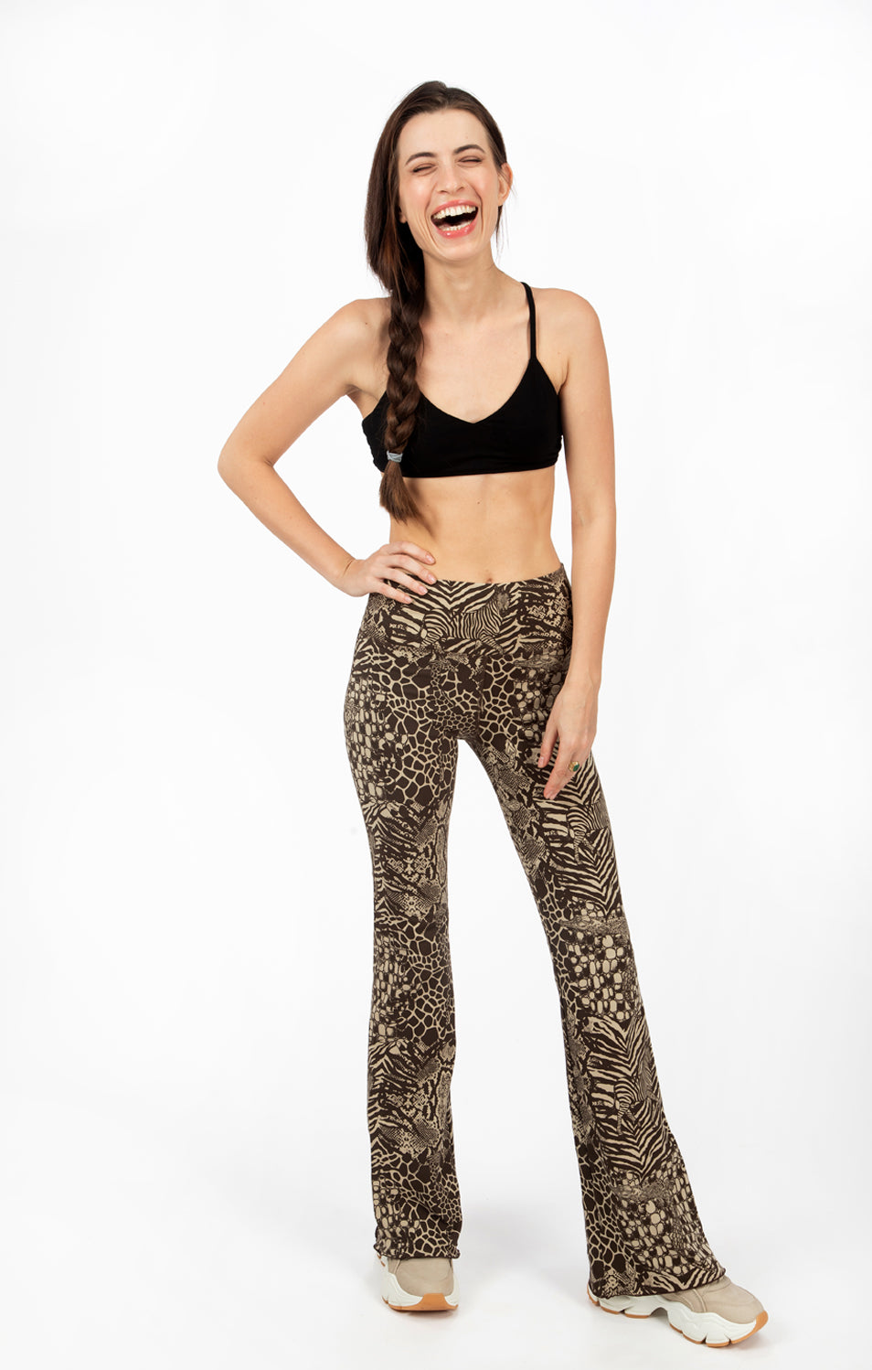 A woman wearing Funky Simplicity wild animal-print flared leggings in cream brown color with black spider bra-top shown from the front.