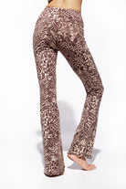 A woman wearing Funky Simplicity wild animal-print flared leggings in cream brown color shown from the back.