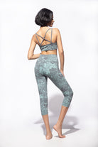 Woman wearing Nagomi Capri leggings in Light Blue (mizu) and light grey. Worn with a matching Cross back bra from Funky Simplicity shown from the back