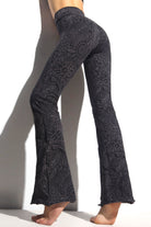 A woman wearing Funky Simplicity tribal-print flared leggings in grey black color shown from the BACK