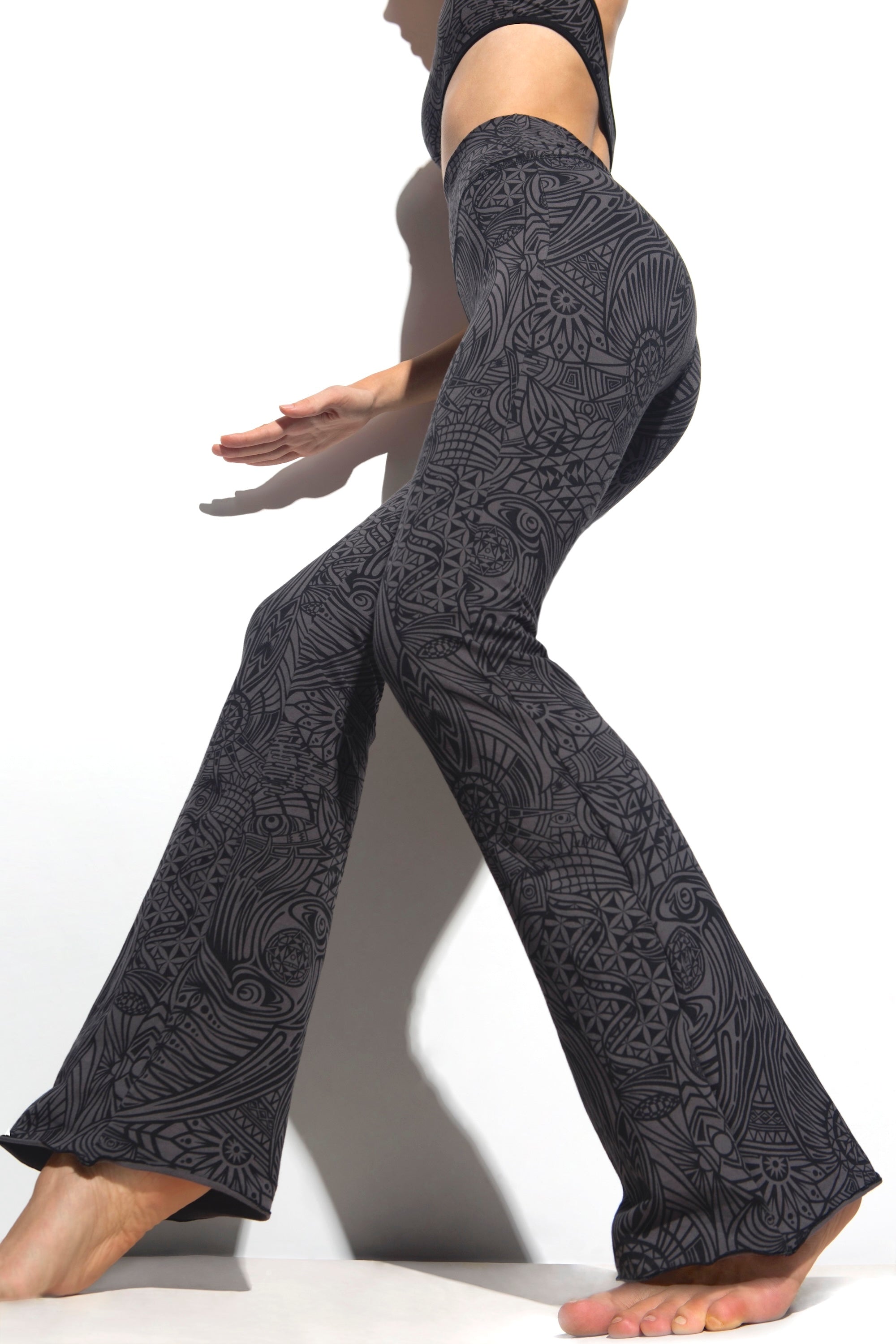 A woman wearing Funky Simplicity tribal-print flared leggings in grey black color shown from the SIDE