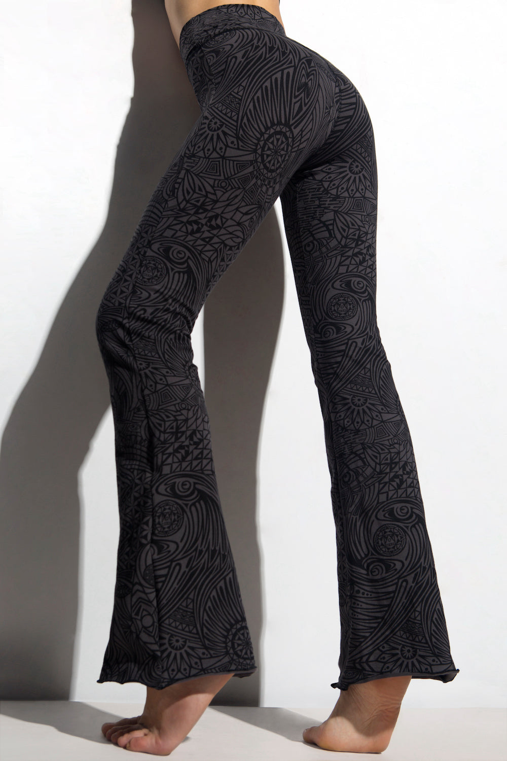 A woman wearing Funky Simplicity tribal-print flared leggings in grey black color shown from the back.