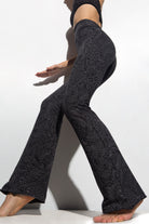 A woman wearing Funky Simplicity tribal-print flared leggings in grey black color shown from the side.